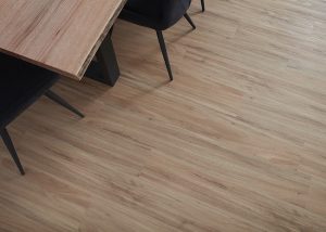 An overhead shot of the corner of a wood topped dining table with black chairs. The flooring in the image is Imagine Floors by Airstep Naturale Plank 3.0 Tallowwood Luxury Vinyl Plank Flooring.